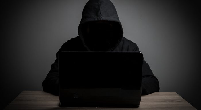 Hacker work front of his laptop computer with dark face. Hacker work front of his laptop computer with dark face.